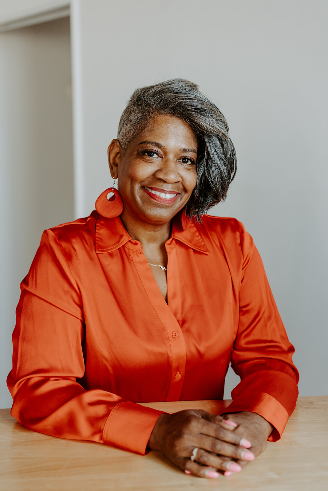 Cecilia Stanton Adams, Founder & Turning Point Strategist, in an orange silk blouse smiling warmly