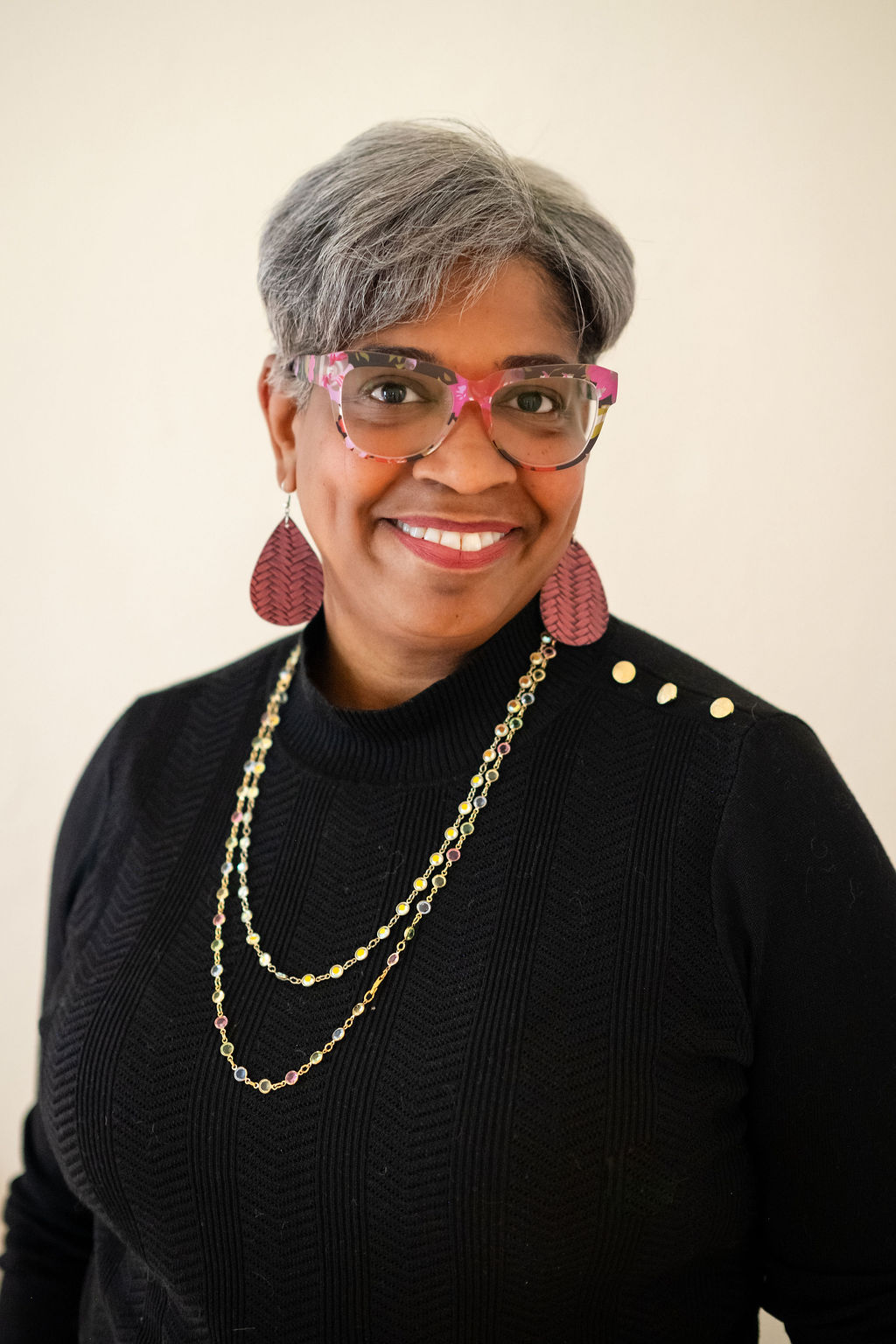 Cecilia Stanton Adams, Founder & Turning Point Strategist, wearing pink patterned glasses and a black knit top
